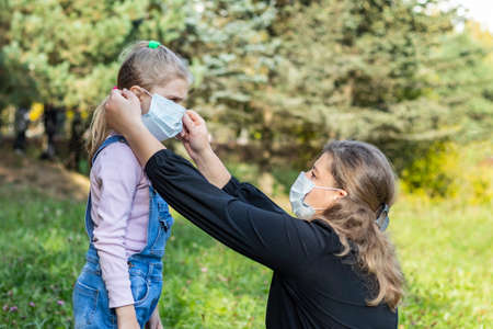 natural light. mom puts on a medical mask for a child with white hair.の写真素材