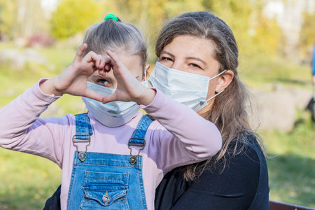 natural light. mom puts on a medical mask for a child with white hair.の写真素材