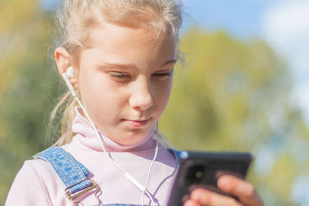 Portrait of a young beautiful Caucasian happy girl about 10 years old with long blonde hair and...