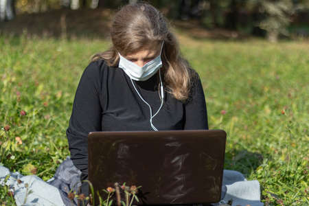 Portrait of a beautiful middle-aged woman with long hair who is working at a laptop. she sits on the...