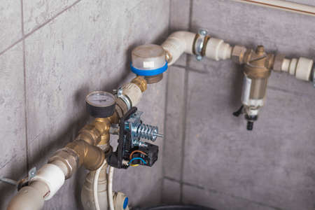 there is a pipe with water on the tiled wall. a water meter is also installed. automation is connected to ensure safety and maintain the desired pressure in the system.の写真素材