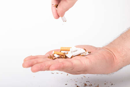 a human hand. the man on her hair. she breaks the cigarettes, and pours them into the other palm. on a white background. close-up.の写真素材
