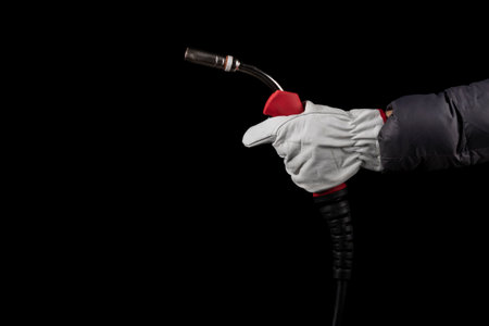 dark background. a human hand in white gloves holds a burner that feeds wire for welding parts.close-upの写真素材