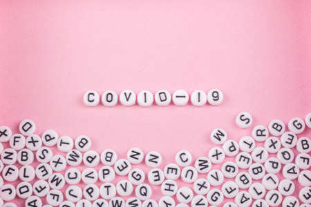 the words covid 19 are laid out in letters on a pink or white background. there are a lot of toy...