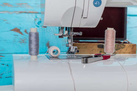 sewing machine. a foot and a needle with a thread in the center of attention. close up. there is a...