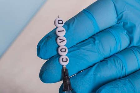 the girl is a doctor in blue gloves holding a syringe with an injection against the disease. on the needle are children's toy letters with the inscription.の写真素材
