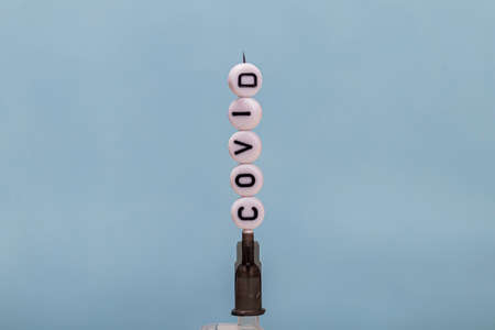 a syringe with an injection against the disease. on the needle are children's toy letters with an inscription. close up.の写真素材