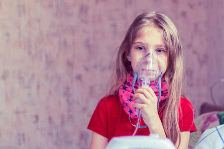 home environment. a girl with white hair is breathing through a medical mask. inhaler for cough and...