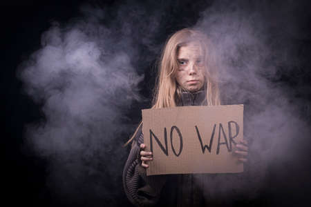 lots of smoke. A frustrated little girl, a homeless child with a dirty face, raises a banner with...