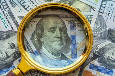 one hundred dollars. a magnifying glass in a gold frame. close up.の写真素材