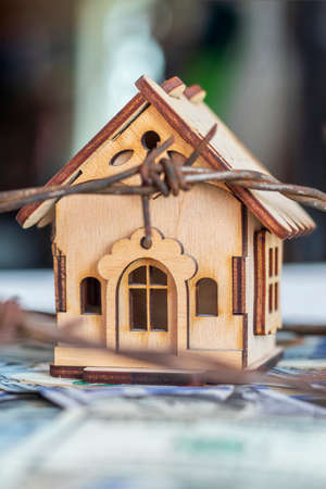 100 dollars. wooden toy house, wire with thorns. seizure or selection of propertyの写真素材