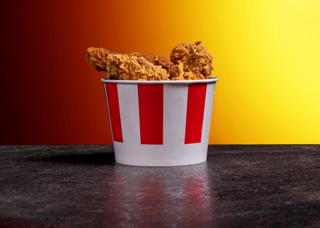 background, night, darkness. shot in a dark key. Chicken wings and barbecue legs in a bucket on a...