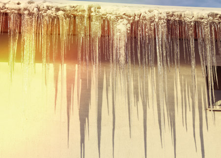 soft focus. natural color. country house. big brown roof. white snow. huge icicles hang downの写真素材