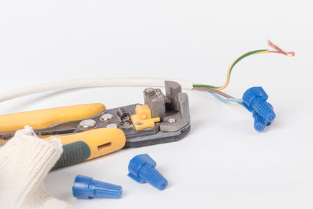 white background. electrical wires. the master removes the insulation with the help of a tool. close...