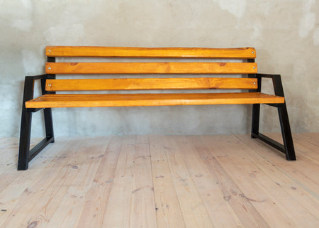 natural light. a bench made of metal and painted black. the wood is covered with yellow varnish and impregnation and slightly agedの写真素材
