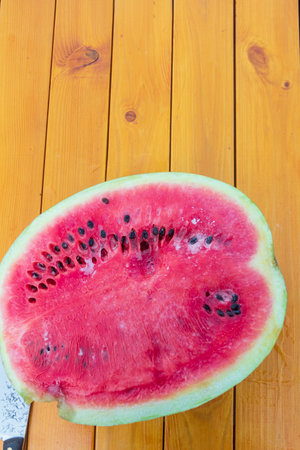 the rotten watermelon is cut and lies on a yellow wooden table. in the fresh air.の写真素材
