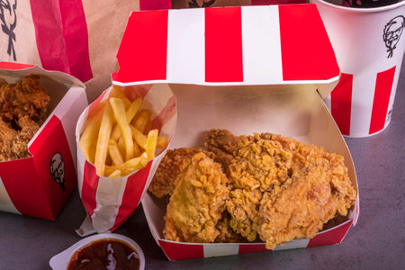 Minsk, Belarus June 19, 2024: black background, night. Lots of hot wings or strips of KFC chicken in a KFC Kentucky Fried Chicken fast food bucketのeditorial素材