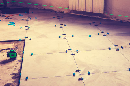 Laying floor tiles. Linear level. Green hand glovesの写真素材