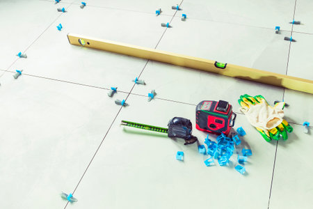 Laying floor tiles. Linear level. Green hand glovesの写真素材