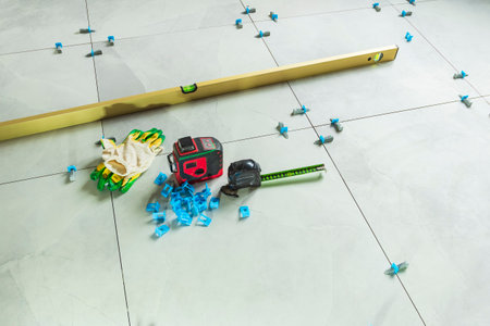 Laying floor tiles. Linear level. Green hand gloves