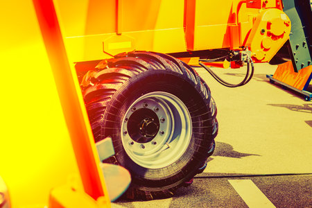 A close-up view of a large tractor tire shows its rugged tread pattern and strong build. The tire is part of a modern tractor showcased at an agricultural equipment event.の写真素材
