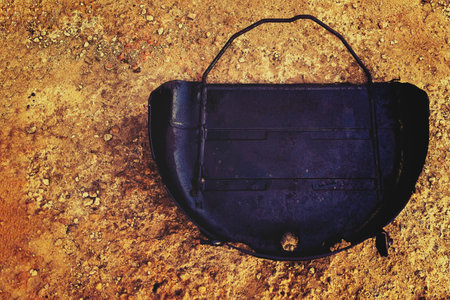 Old metal container resting on the ground among gravel, showcasing rust and wear from years of use in outdoor environmentsの写真素材