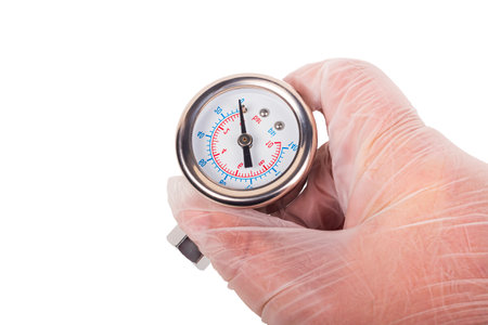 A gloved hand holds a pressure gauge against a vibrant, multi-colored background. The device displays measurements clearly, indicating precise readings in a professional setting.の写真素材