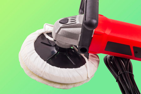 Close-up of a polishing machine designed for automotive detailing. The tool features a wool pad,...