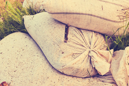 Sacks filled with freshly collected grass clippings are stacked in a field with bright green grass...