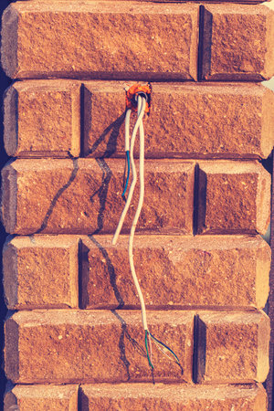 Construction site shows exposed electrical wiring near a brick wall during late afternoon sunlight...