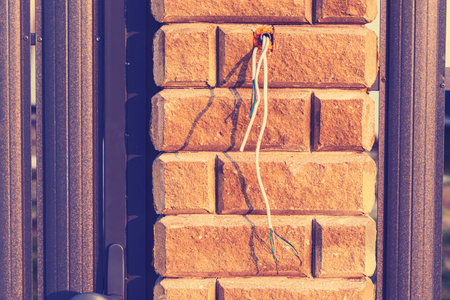 Electrical wires are exposed from a damaged intercom system on a residential building's exterior....