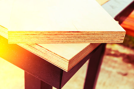Wooden boards resting on a textured surface in a well-lit workspace during daytimeの写真素材
