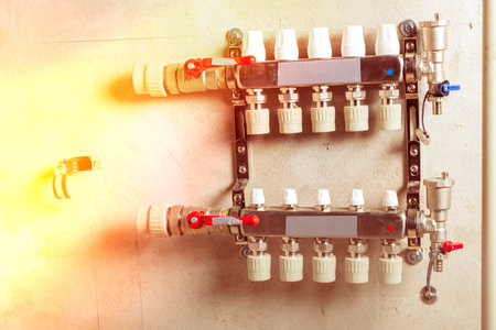 Modern plumbing distribution manifold installed on a concrete wall in a residential buildings utility areaの写真素材