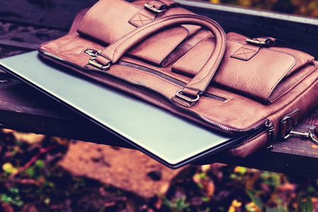Brown leather bag with laptop left unattended in a park during the afternoonの写真素材