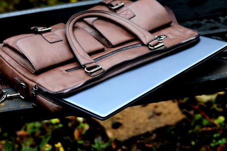 Brown leather bag with laptop left unattended in a park during the afternoonの写真素材