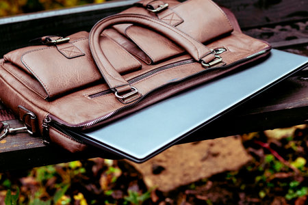 Brown leather bag with laptop left unattended in a park during the afternoonの写真素材