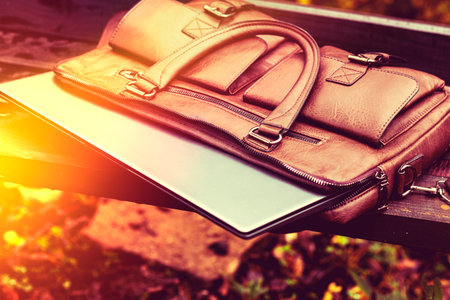 Brown leather bag with laptop left unattended in a park during the afternoonの写真素材