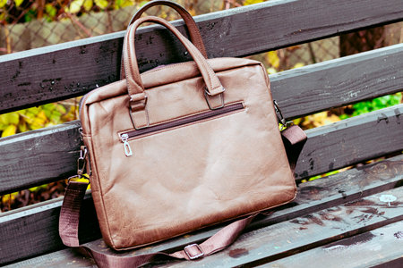 Brown leather bag with laptop left unattended in a park during the afternoonの写真素材