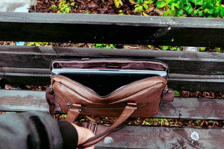 Brown leather bag with laptop left unattended in a park during the afternoonの写真素材