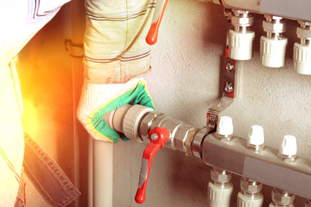 A person in gloves is using a pipe cutter during a home improvement task. The setting indicates a...