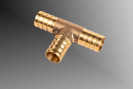 A brass T-fitting is shown on a plain background. This piece connects three tubing ends, commonly...