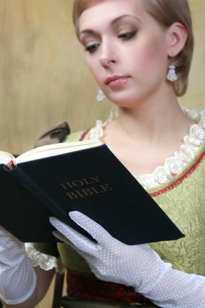 The girl reads the bible. Focus on the book.