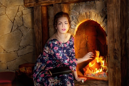 The girl near a fireplace with the bookの写真素材