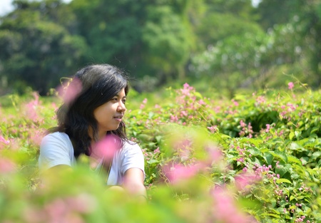 Sweet young woman sitting in green rural field の写真素材