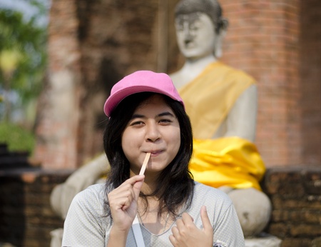 Beautiful young girl and buddha at Wat Yai Chai Mongkol Temple. Ayutthaya - Thailand の写真素材