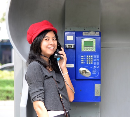 Young happy woman calling from public phone, outdoor shot の写真素材
