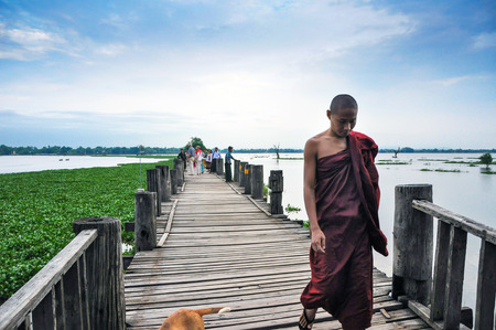 MANDALAY, MYANMAR - October 9, 2013  Unidentified young monk walking on U Bein Bridge, Myanmar  The...