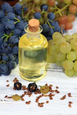 Grape seed oil and grape seeds in front, fresh grapes aroundの写真素材