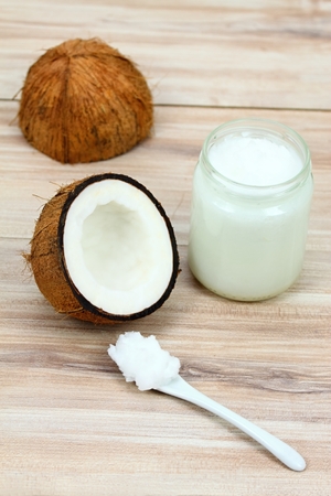 Organic coconut oil from coconuts in a white glass jar, fresh coconut cut in half and its pieces
