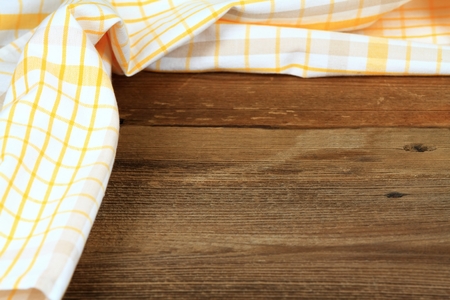 Dish cloth in yellow and white on brown wooden table. Linen tea towel on board, good for backgroundの写真素材